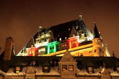 a large building lit up at night with christmas lights on it's roof and windows