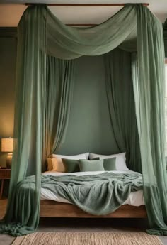 a canopy bed with green drapes and pillows