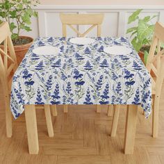 a blue and white table cloth with flowers on it in front of potted plants