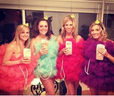 four beautiful women dressed in colorful dresses holding cell phones and posing for a photo together