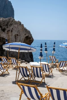 beach chairs and umbrellas are lined up on the sand near the water's edge