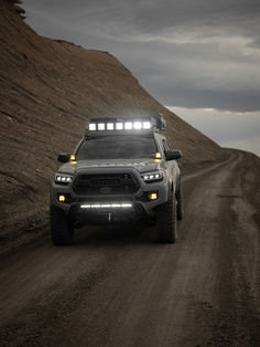 a truck driving down a dirt road with lights on it's headlamps