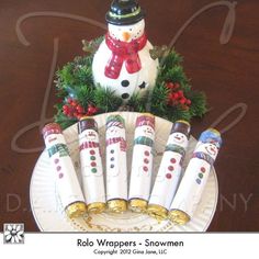 a paper plate with snowmen on it sitting next to some candy rolls and a snowman