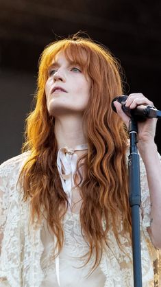 a woman with long red hair holding a microphone