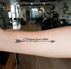 a woman's arm with an arrow tattoo on it that says, i conquer from within