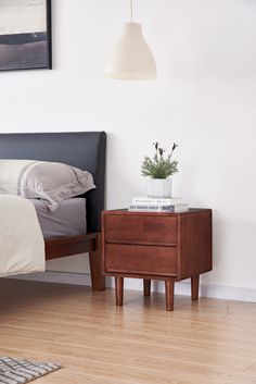 a bed sitting next to a night stand on top of a hard wood floor