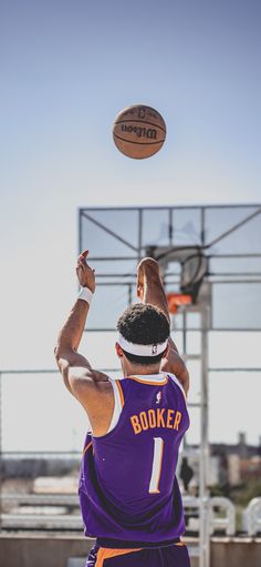 a man in purple jersey throwing a basketball into the air