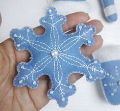 a hand holding a blue snowflake ornament