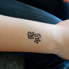 a woman's arm with a tattoo design on the left side of her arm