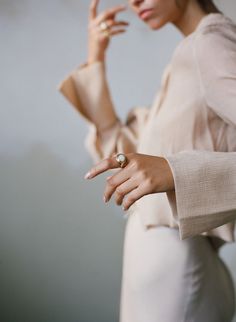 a woman is holding her hand out and pointing to the side with both hands while wearing a ring