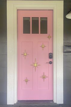 a pink door with gold stars painted on the front and side panels, along with a light fixture