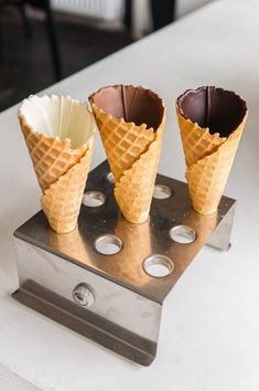 three ice cream cones sitting on top of a metal stand