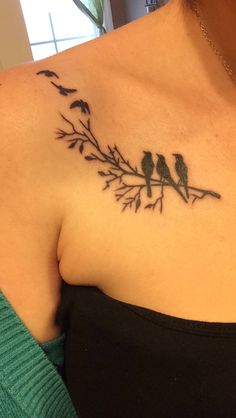 a woman's chest with two birds sitting on a branch