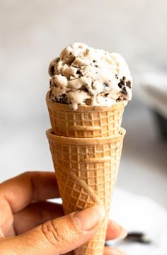 a hand holding an ice cream cone with chocolate chip cookies