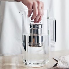 a woman is pouring water into a glass pitcher