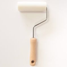 a white paint roller attached to a wall with a wooden handle on the back of it