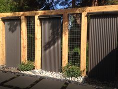 a fence made out of metal and wood with some plants growing on the top one side