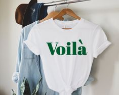 VOILÁ FRENCH STYLE  T - SHIRT T-SHIRT IS A STATEMENT OF YOUR STYLE!  This PREMIUM QUALITY and extra COMFY unisex tee is SOFT FABRIC, modern fit, and feel AMAZING TO WEAR. T-shirt is 100% „MUST HAVE" item for perfect EVERYDAY stylish OUTFITS and we believe you LOVE this one.  Please refer to our SIZE CHART in the thumbnails for EXACT DIMENSIONS or SIZE UP if you want oversize or flowy. We made this item PERSONALLY FOR YOU so please check the DETAILS and especially the SIZE before you order. THANK Summer Gift T-shirt With Text Print, Summer Text Print T-shirt For Gift, Summer Slogan Top As Gift, Slogan Tees, French Gifts, Style Français, Paris T Shirt, Slogan Tshirt, Statement Tshirt