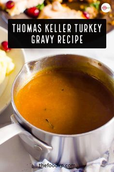 a pot filled with gravy sitting on top of a white table next to a plate