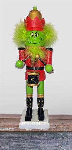 a green and red nutcracker is standing on a white base