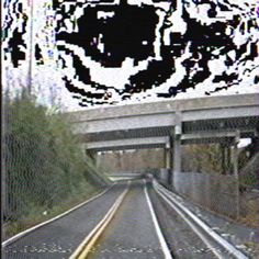 a train track going under a bridge with graffiti on the wall and trees in the background