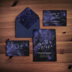 the wedding stationery is laid out on a wooden table with space themed cards and envelopes