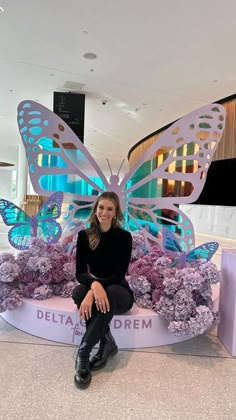 a woman sitting on top of a bench covered in purple flowers and butterfly wings with the words delta dream above her