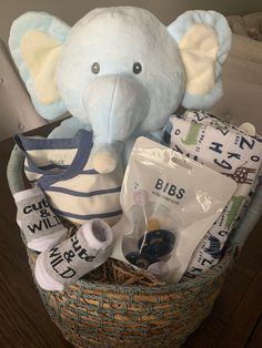 a stuffed elephant sitting in a basket filled with baby items