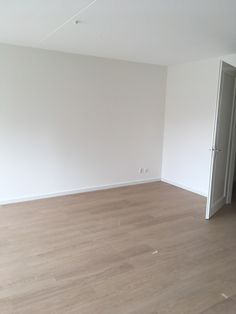 an empty room with hard wood floors and white walls