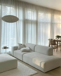 a living room filled with white furniture and curtains