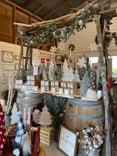 christmas decorations are on display in a shop with wooden barrels and snowflakes hanging from the ceiling