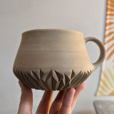 a person holding up a clay cup in their hand