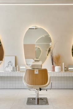 a chair in front of a mirror with lights on the wall and plants behind it