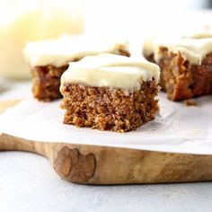 four pieces of carrot cake sitting on top of a piece of parchment paper next to a knife and fork