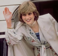 a woman wearing a white suit and holding her hand up in the air