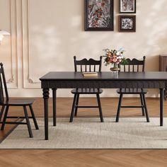 a dining room table and chairs in front of a wall with pictures on the wall