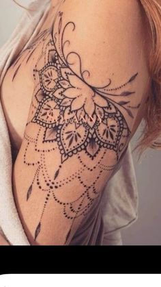 a woman's shoulder with an intricate tattoo design on the arm and shoulder area