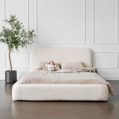 a bed with a stuffed animal on top of it next to a potted plant