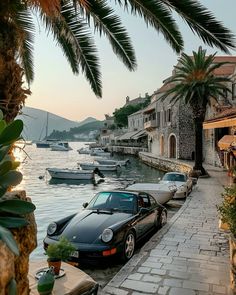 a black car parked on the side of a road next to a body of water