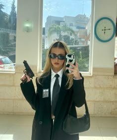 a woman in a suit and sunglasses holding up a cell phone