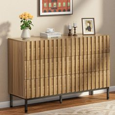 a wooden dresser with drawers and pictures on the wall