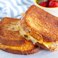 two grilled cheese sandwiches with strawberries in the background