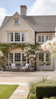 a large house with white flowers in the front yard and windows on either side of it