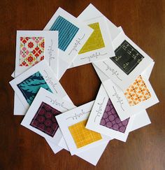 six cards with different designs on them sitting on top of a wooden table next to each other