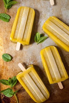 three popsicles with lemon and mint sitting on a table next to some ice cream