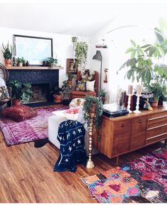 a living room filled with lots of furniture and plants on top of it's wooden floors