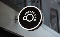 a black and white coffee sign hanging from the side of a building next to a window