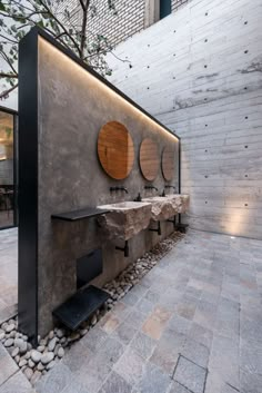 an outdoor bathroom with three sinks and mirrors on the wall, surrounded by stone pebbles