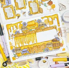 an open notebook with honey themed pages and markers on the desk next to some pens