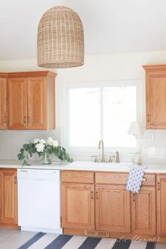 a kitchen with wooden cabinets and white counter tops next to a striped rug on the floor